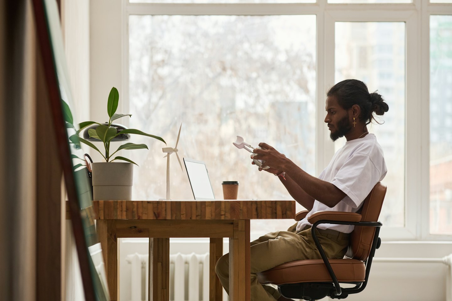 Designer examines a white 3D-printed mechanism at his desk.